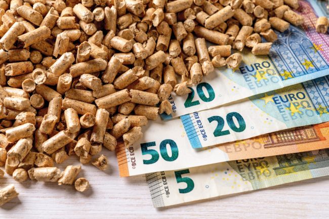 Heap of wood pellets and euro paper banknotes top view. Costs of organic biofuel from compressed sawdust. Ecological heating, alternative energy concepts. Bio fuel costs, buy and sell pellets.