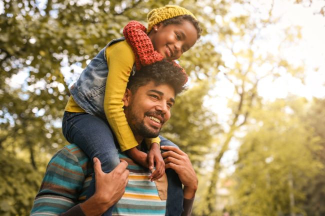 African American father with daughter on meadow.