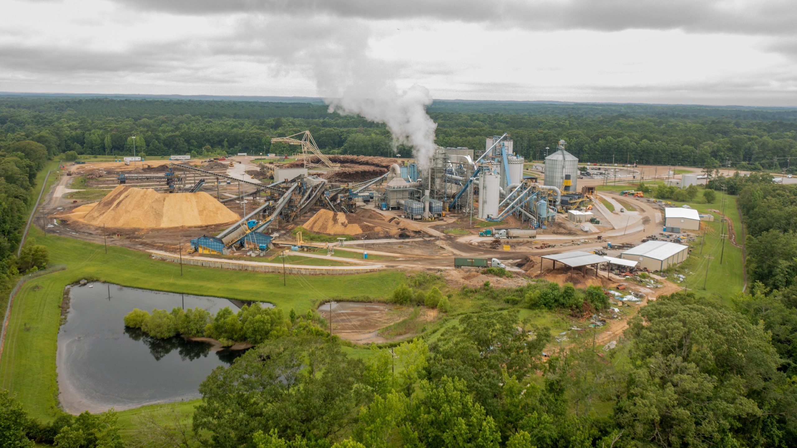 wood pellet manufacturing plant with smoke, wood dust, and logs