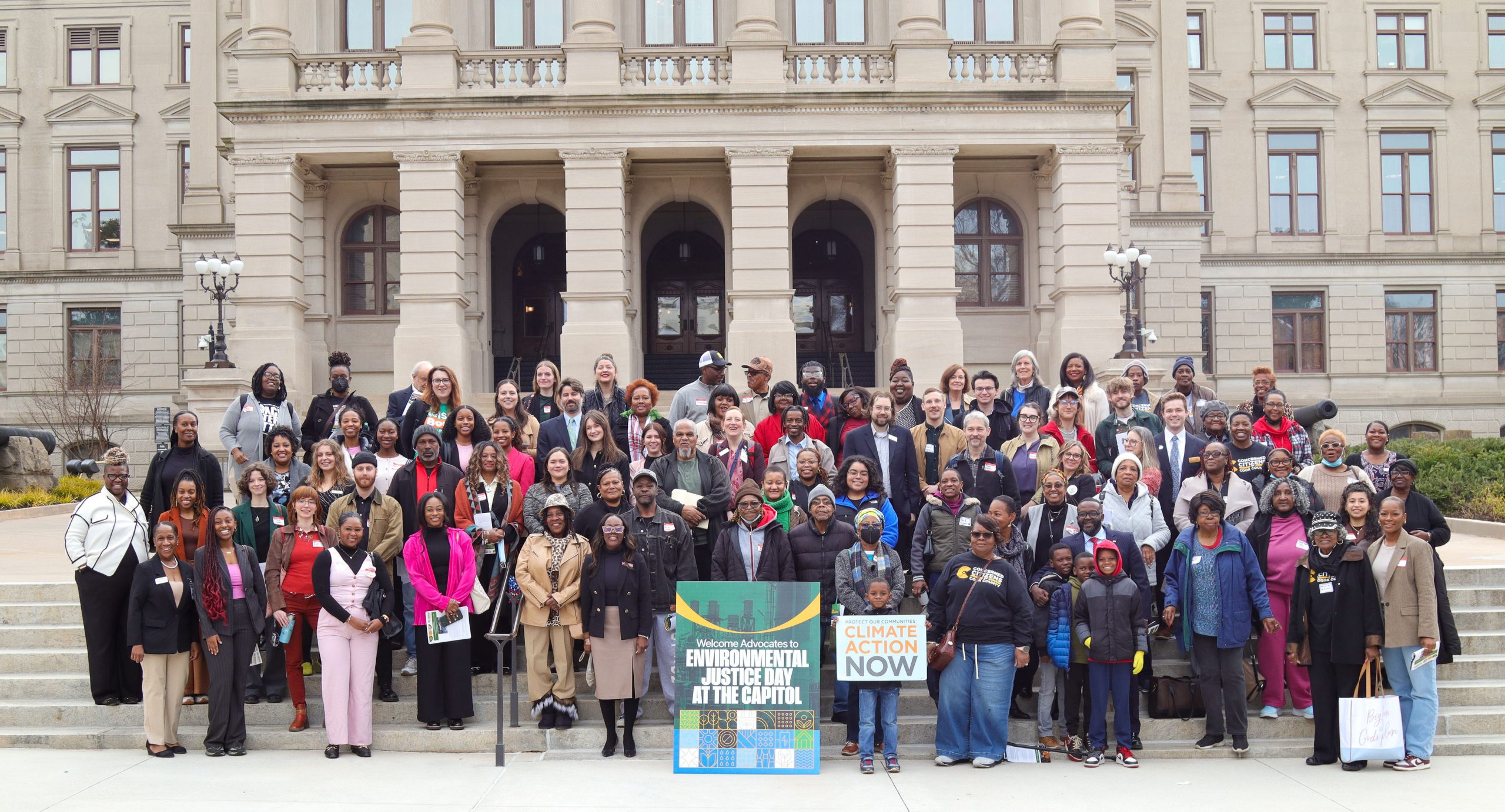 group of people standing in front of the Georgia Capitol building behind signs for environmental justice and climate action