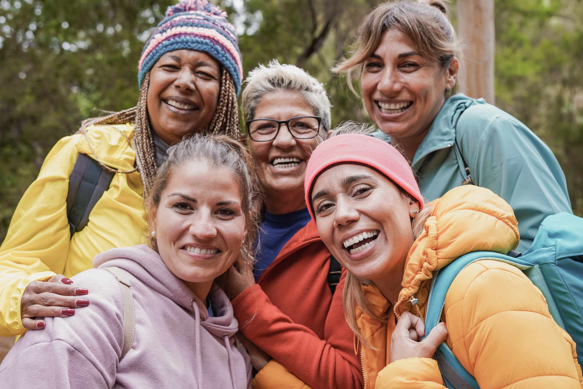 multiracial group of smiling women in the woods